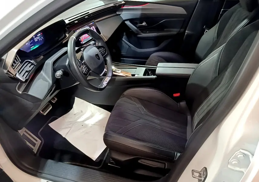 Vue intérieure côté conducteur de la Peugeot 308 PHEV 180 GT 2022, sièges noirs et tableau de bord digital lumineux.