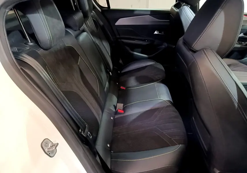 Vue côté gauche sur les sièges arrière noirs avec surpiqûres vertes d'une Peugeot 308 PHEV 180 E-EAT8 GT blanche.