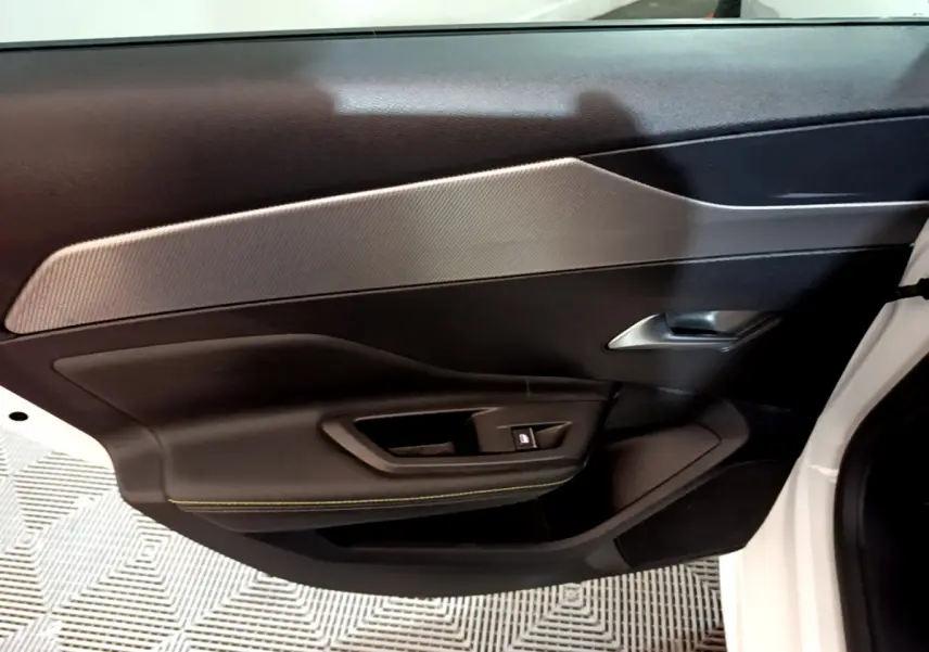 Vue rapprochée de la porte côté gauche blanche d'une Peugeot 308 PHEV 180 E-EAT8 GT avec garniture noire et insert gris.