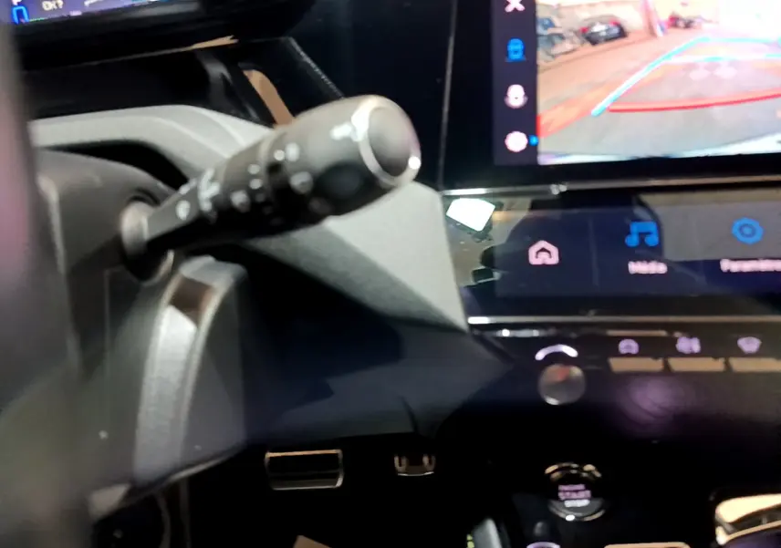 Détail intérieur montrant la commande au volant et l'écran tactile avec caméra de recul de la Peugeot 308 PHEV 180 GT.
