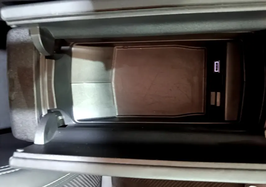 Gros plan sur la console centrale noire de la Peugeot 308 PHEV 180 E-EAT8 GT, avec compartiment ouvert et port USB visible.