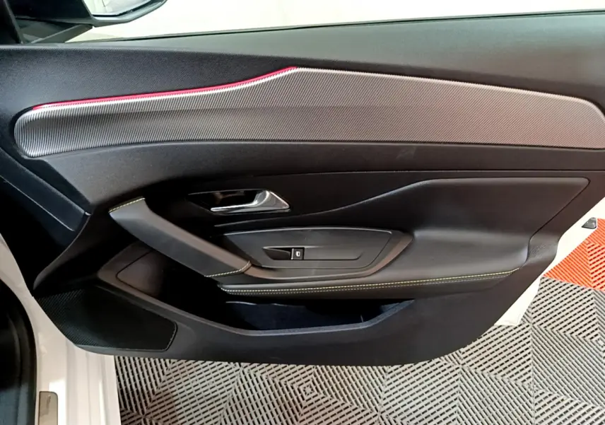 Gros plan sur la porte côté gauche blanche de la Peugeot 308 PHEV 180 E-EAT8 GT avec surpiqûres vertes et insert décoratif gris.
