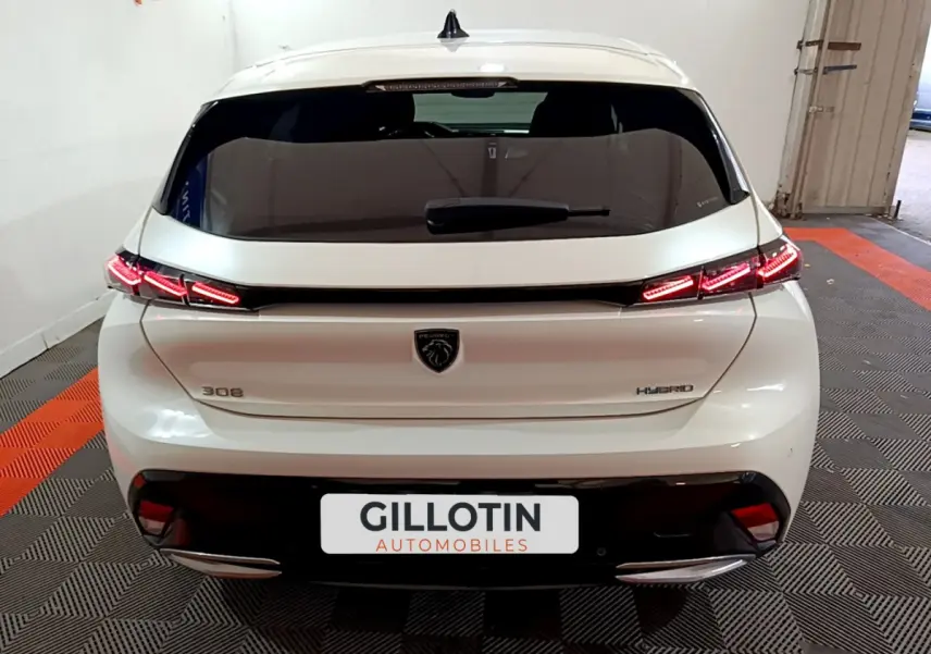 Vue arrière d'une Peugeot 308 PHEV 180 E-EAT8 GT blanche avec feux LED distinctifs et logo lion central.