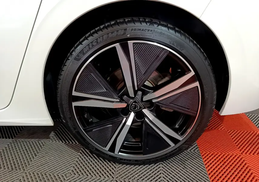 Gros plan sur la roue arrière droite blanche d'une Peugeot 308 PHEV 180 E-EAT8 GT avec jante noire et argentée design moderne.