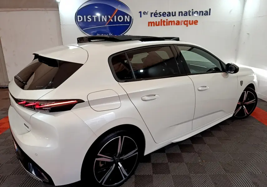 Peugeot 308 PHEV 180 GT blanc vue 3/4 arrière droit avec toit ouvrant et feux arrière LED allumés.