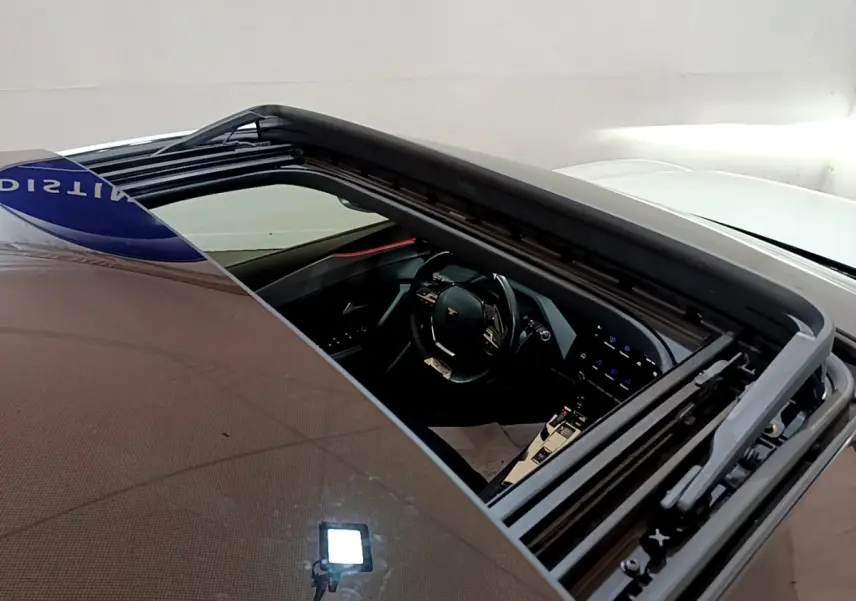 Vue plongeante sur l'intérieur noir du Peugeot 308 PHEV blanc 2022 via toit ouvrant panoramique ouvert.