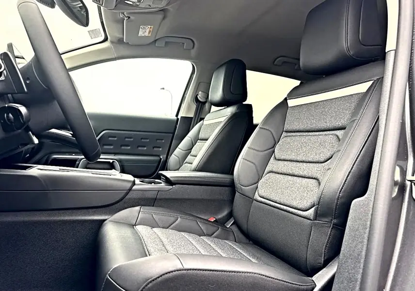 Intérieur avant du Citroën C5 Aircross 2025, sièges cuir et tissu gris, vue côté conducteur avec accoudoir central.