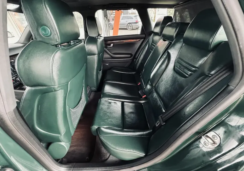 Vue intérieure côté droit des sièges arrière en cuir vert foncé de l'Audi S4 Avant 2004 avec détails de finition bois.