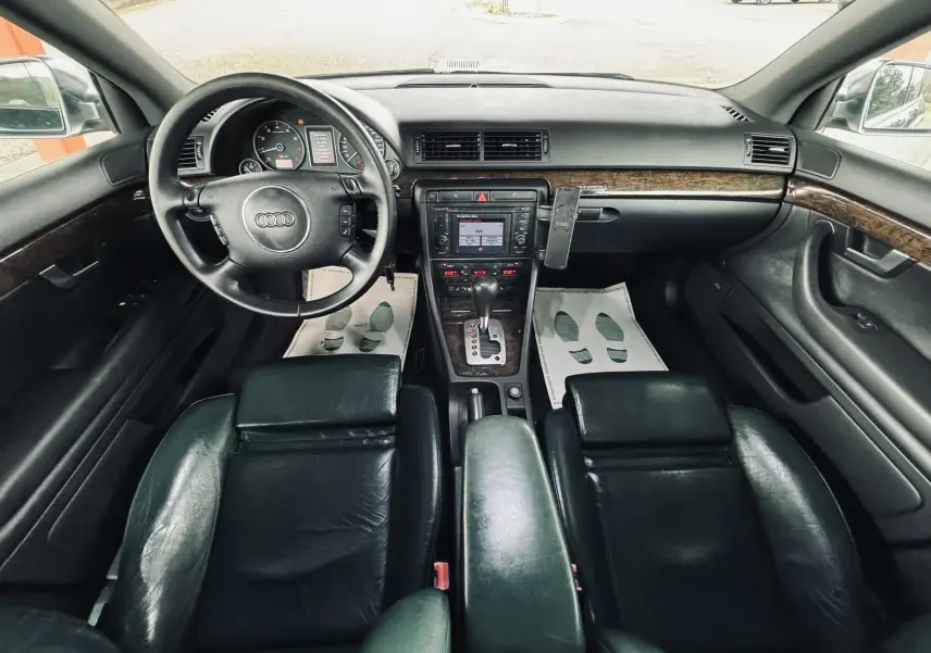 Vue intérieure avant de l'Audi S4 Avant 2004 avec tableau de bord noir et sièges cuir foncé.