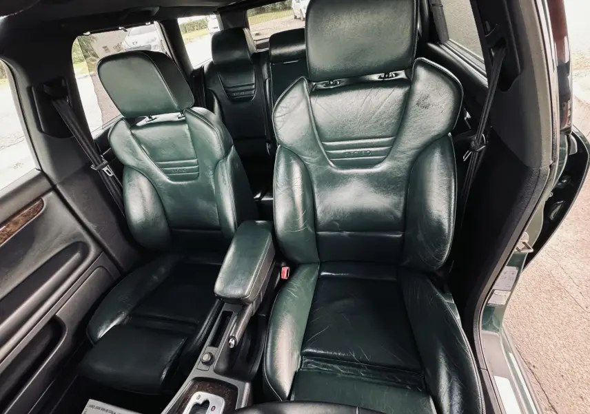 Vue intérieure sur les sièges avant en cuir vert foncé de l'Audi S4 Avant, avec accoudoir central et portière ouverte côté droit.