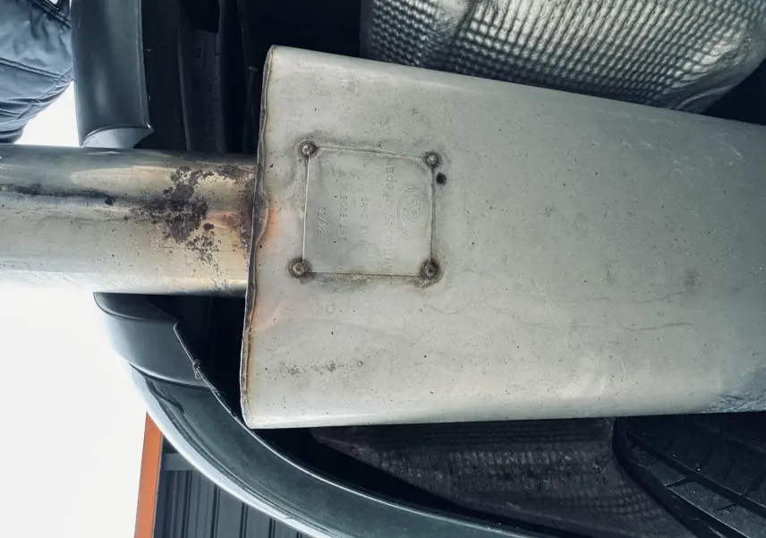 Gros plan sur l'échappement sport en acier sous le coffre d'une Audi S4 Avant verte de 2004.