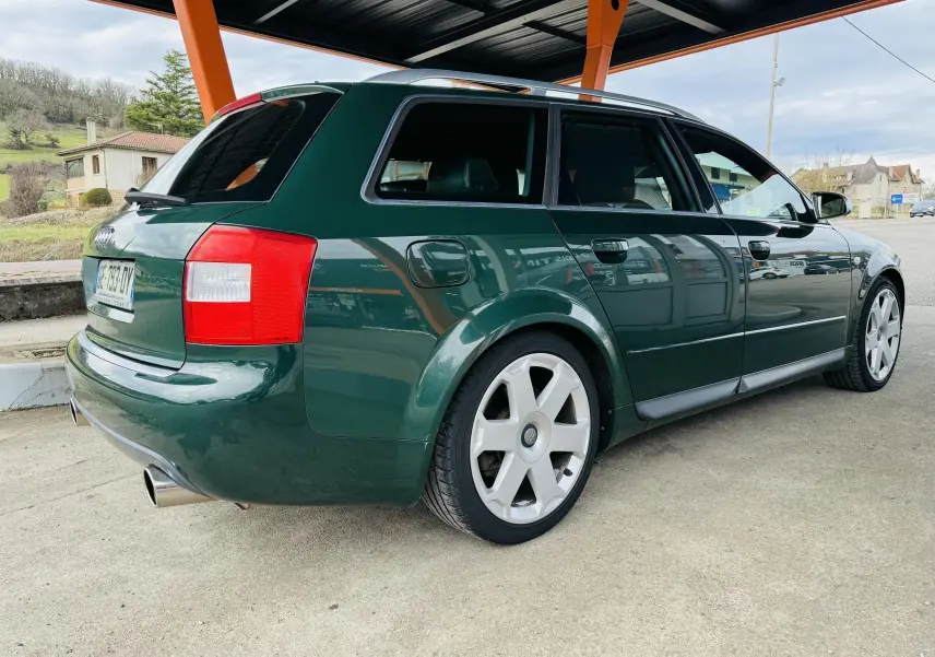 Vue 3/4 arrière droite d'une Audi S4 Avant 2004 verte avec jantes alliage et échappement sport visible.