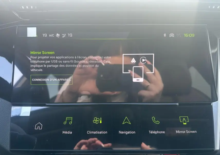 Écran tactile central de la Peugeot 308 blanche, affichant le menu Mirror Screen avec commandes multimédia et navigation.