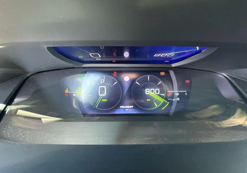 Combiné numérique 3D du tableau de bord Peugeot 308 blanc, affichant vitesse et régime moteur au ralenti.