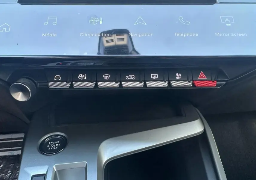 Vue rapprochée de la console centrale de la Peugeot 308 blanche, avec boutons de commande et bouton start/stop visibles.