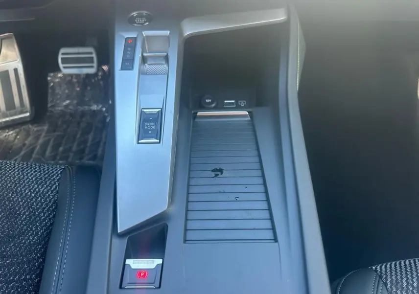 Vue plongeante sur la console centrale de la Peugeot 308 blanche, avec commandes Drive Mode et frein électrique visible.