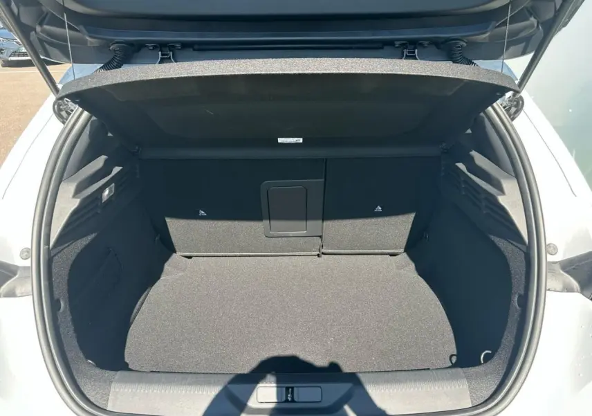 Coffre ouvert d'une Peugeot 308 blanche vue de l'arrière, montrant un espace de chargement propre et spacieux.