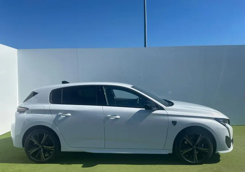 Profil côté gauche d'une Peugeot 308 blanche Okenite avec jantes alliage 18'' Portland et détails noirs brillants.