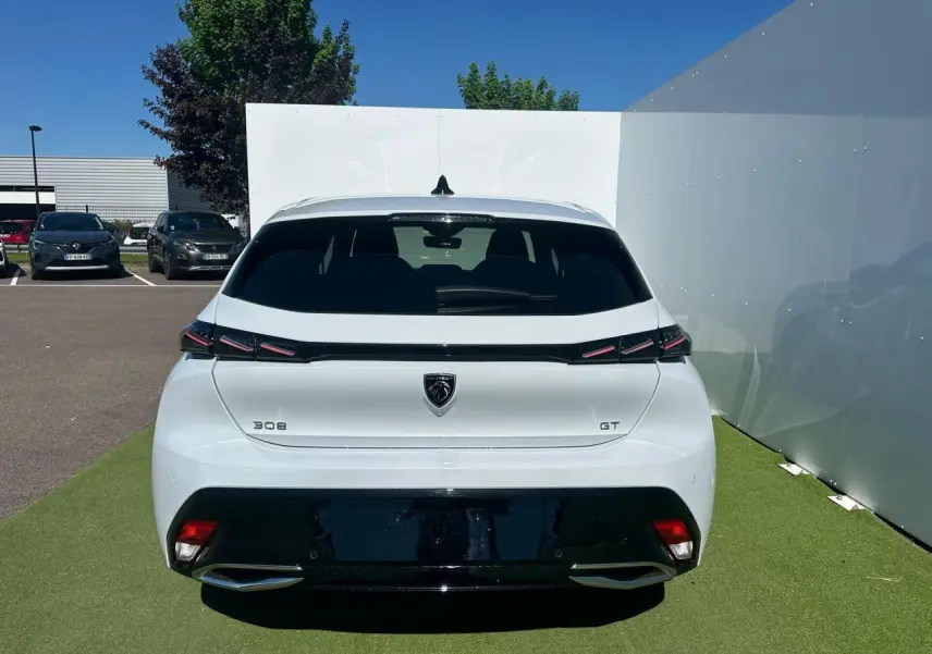 Vue arrière d'une Peugeot 308 GT blanche Okenite avec feux arrière griffés et double sortie d'échappement chromée.