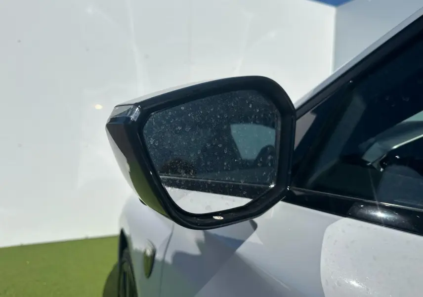 Rétroviseur côté gauche noir brillant sur Peugeot 308 blanche Okenite, vue rapprochée en extérieur.