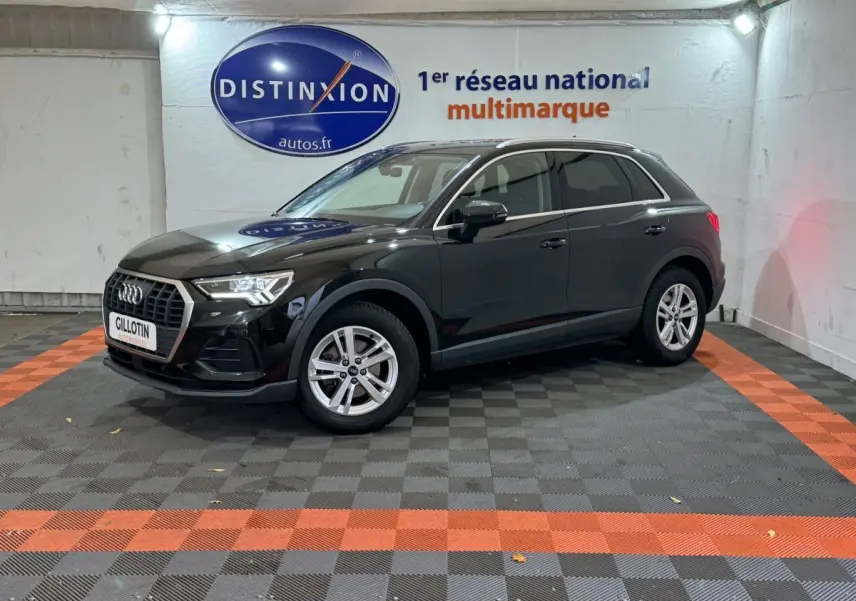 Audi Q3 35 TFSI noir vue 3/4 avant droit dans un showroom avec sol à damier gris et orange.
