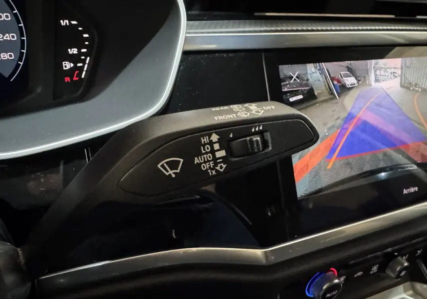 Gros plan intérieur sur le commodo essuie-glace et l'écran de caméra de recul de l'Audi Q3 noir 2022.