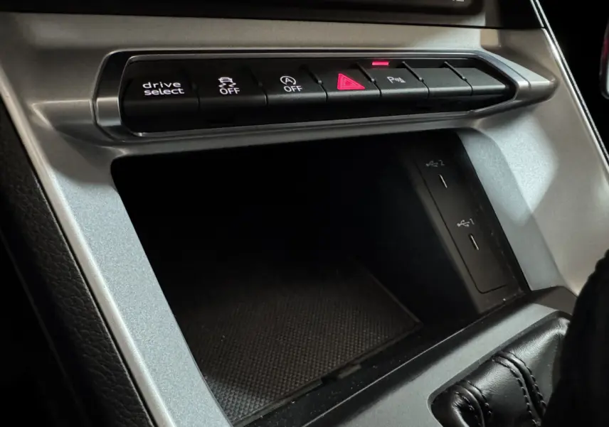 Vue rapprochée de la console centrale argentée avec boutons de contrôle et ports USB dans l’Audi Q3 noir 2022.