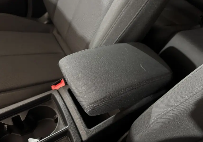 Gros plan intérieur sur l'accoudoir central noir et les sièges tissu gris foncé de l'Audi Q3 35 TFSI 2022.