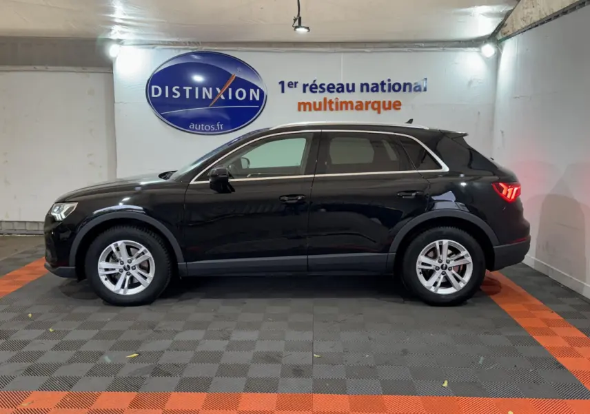 Audi Q3 noir vue de profil côté gauche dans un showroom avec éclairage intérieur et logo Distinxion en arrière-plan.