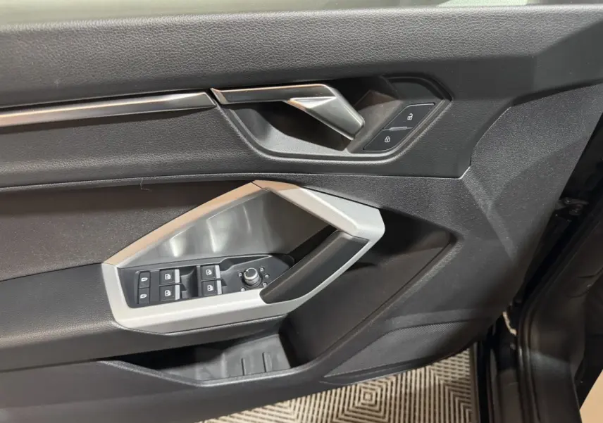 Vue rapprochée de la porte avant gauche noire de l’Audi Q3 35 TFSI avec commandes de vitres et verrouillage.