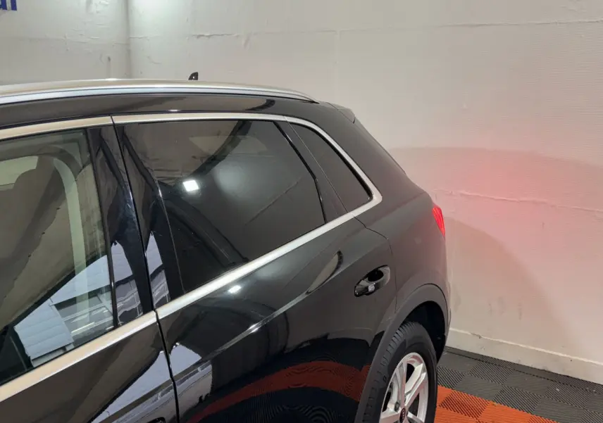 Vue 3/4 arrière côté droit d’un Audi Q3 noir avec vitres teintées et jantes alliage argentées dans un garage.