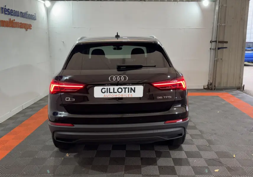 Vue arrière d’un Audi Q3 noir 35 TFSI avec feux LED allumés dans un garage fermé.