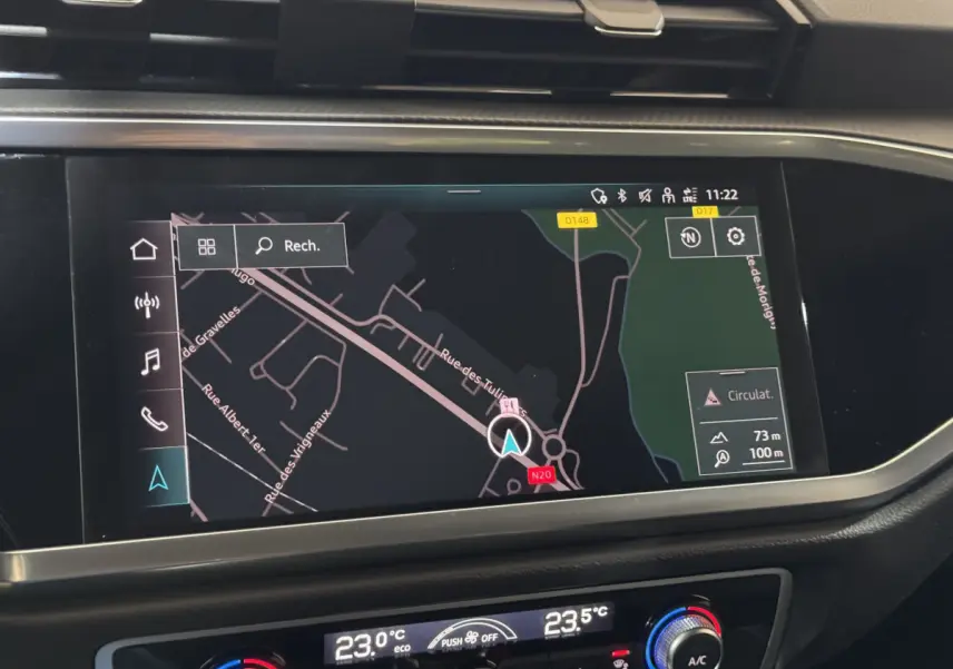 Écran tactile de navigation couleur dans le tableau de bord d’un Audi Q3 noir, vue intérieure centrée.