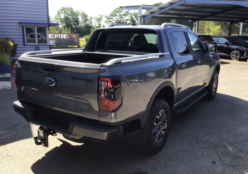 Ford Ranger Double Cabine gris carbone vu de l'arrière droit, avec plateau ouvert et attelage visible.