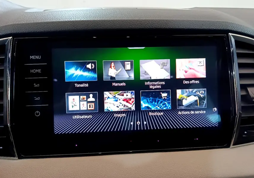 Écran tactile central du tableau de bord du Skoda Karoq 2023, affichant le menu principal en intérieur beige.