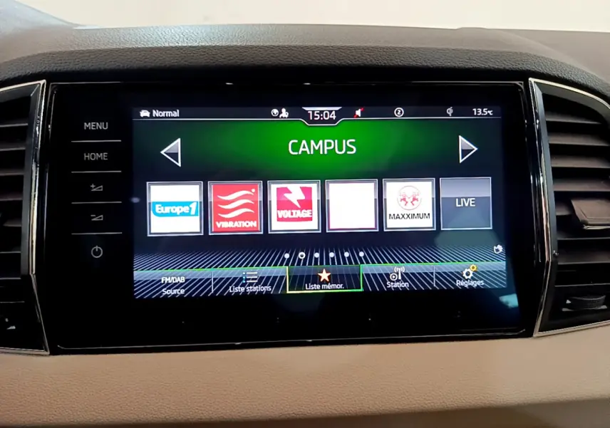 Écran tactile central du tableau de bord beige du Skoda Karoq 2023 affichant les stations radio en mode Campus.