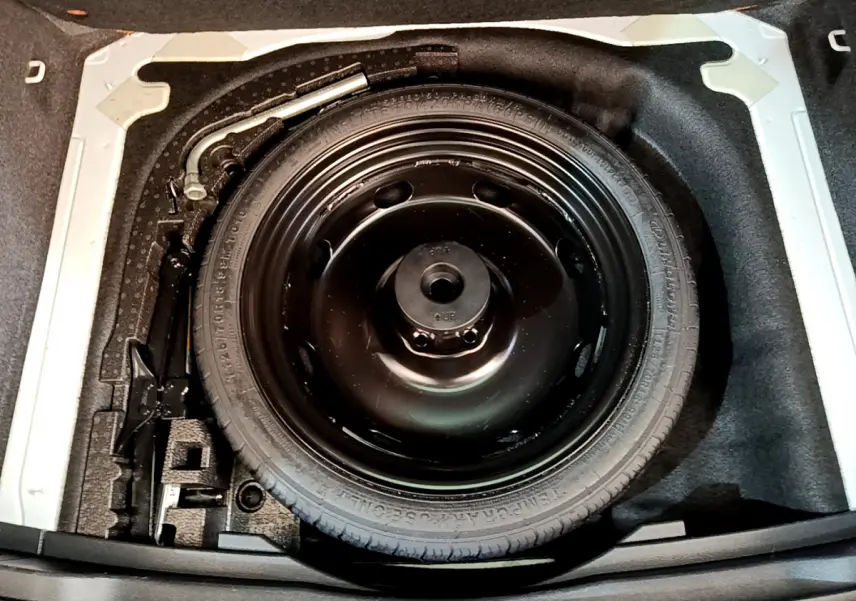 Vue plongeante sur la roue de secours noire dans le coffre du Skoda Karoq blanc 2023, version Style diesel.