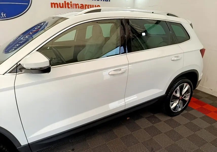 Vue de profil côté gauche du SUV blanc Skoda Karoq 2023 avec jantes alliage et vitres teintées.