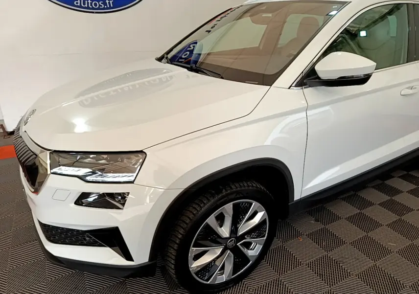 Vue 3/4 avant droit d'un Skoda Karoq blanc avec jantes alliage bicolores et phares LED ellipsoïdaux.