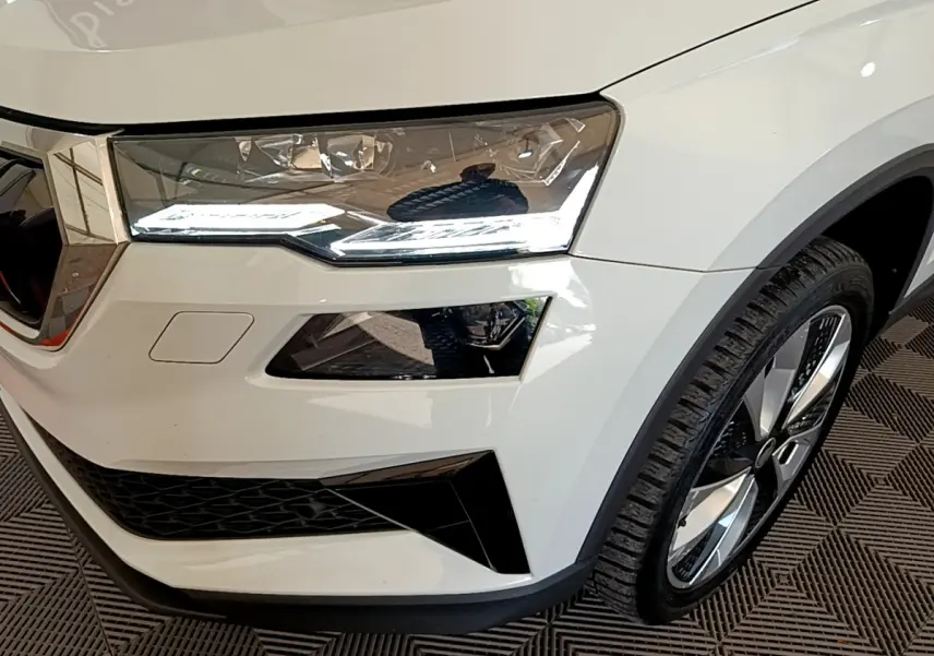 Gros plan sur l'avant droit blanc du Skoda Karoq 2023, mettant en valeur le phare LED et la jante alliage.