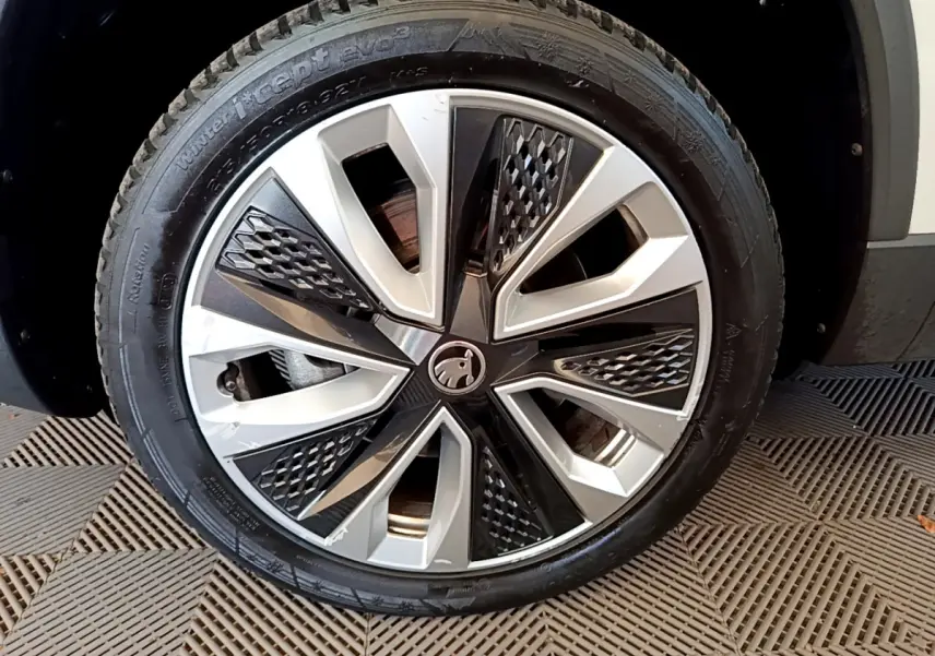 Gros plan sur la roue avant droite du Skoda Karoq blanc, mettant en valeur la jante alliage bicolore au design moderne.