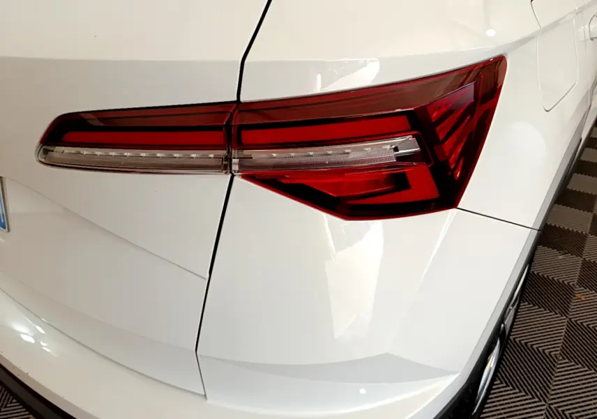 Gros plan sur le feu arrière droit rouge du SUV blanc Skoda Karoq 2023, avec lignes anguleuses et carrosserie lisse.
