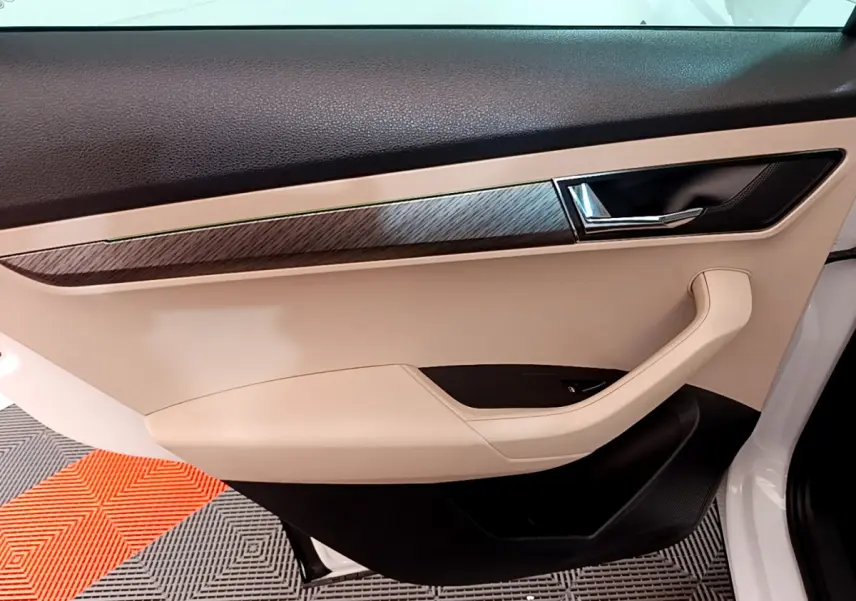 Vue intérieure côté gauche de la porte avant beige et noire avec insert effet bois du Skoda Karoq blanc 2023.