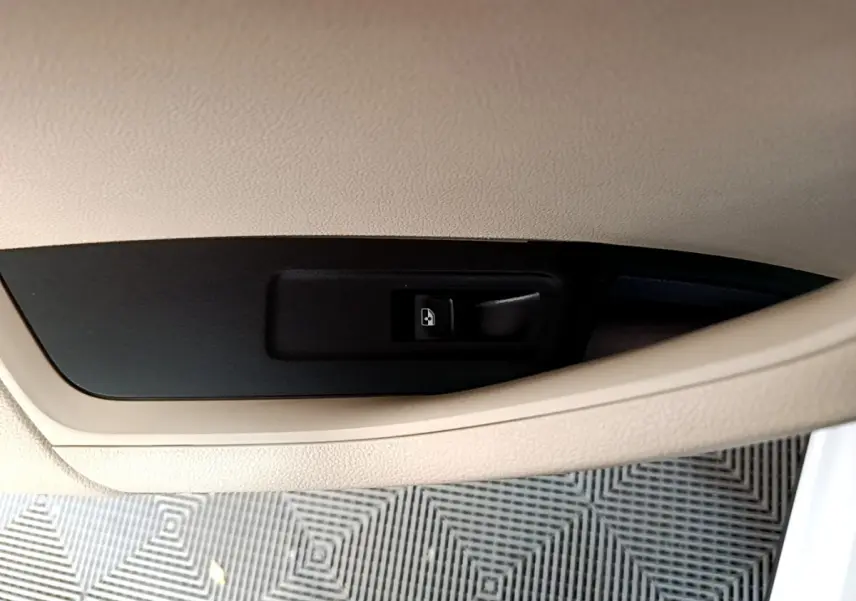 Bouton d'ouverture électrique du coffre sur panneau intérieur beige, SKODA KAROQ blanc 2023 vue rapprochée.