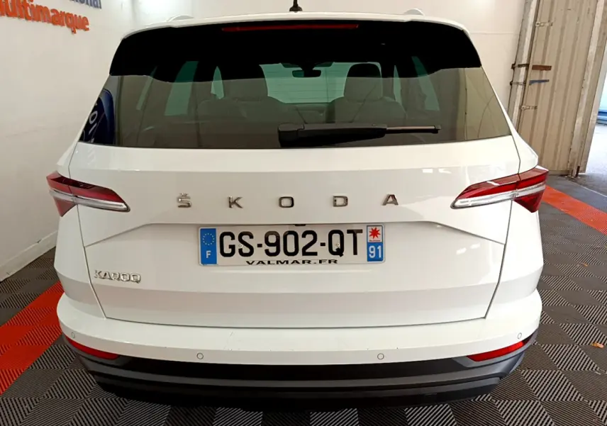 Vue arrière d'un Skoda Karoq blanc avec plaques françaises, feux arrière LED et logo ŠKODA visible.