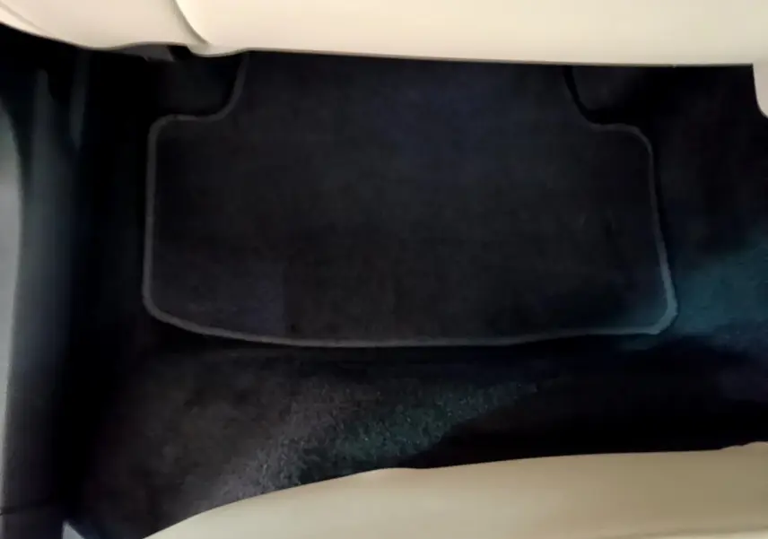 Tapis de sol noir vu de dessus à l'avant droit d'un Skoda Karoq blanc 2023, intérieur clair partiel visible.