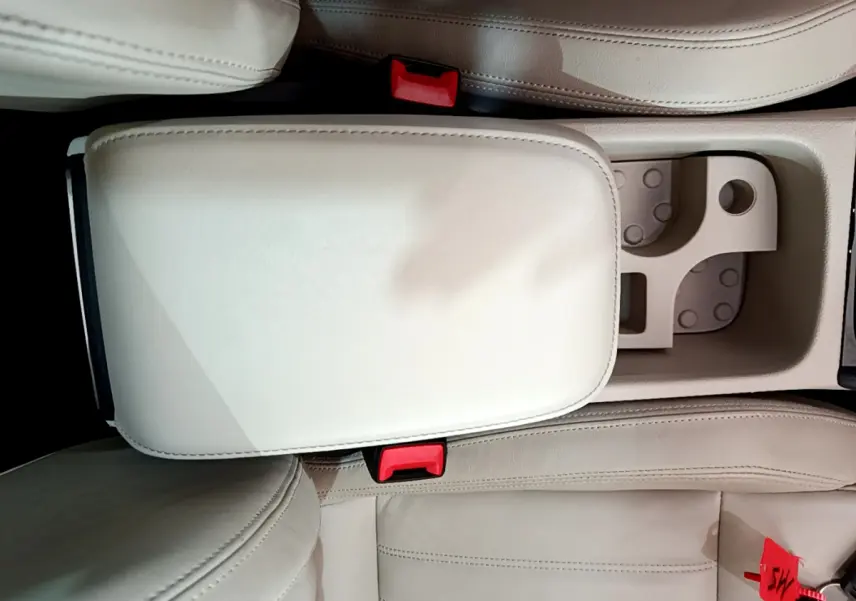 Vue plongeante sur l'accoudoir central beige et les sièges avant en cuir clair d'un Skoda Karoq 2023.