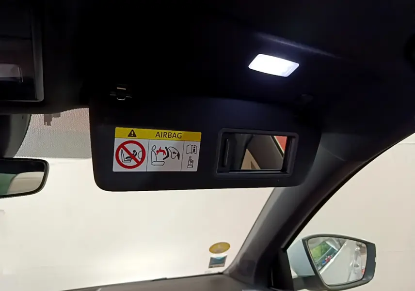 Vue intérieure du pare-soleil côté conducteur avec miroir et avertissement airbag dans un Skoda Karoq blanc 2023.