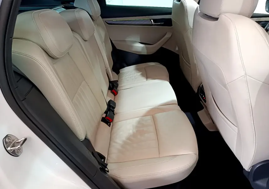 Vue intérieure côté gauche des sièges arrière en cuir beige du Skoda Karoq blanc 2023, avec détails des appuie-têtes et portières.