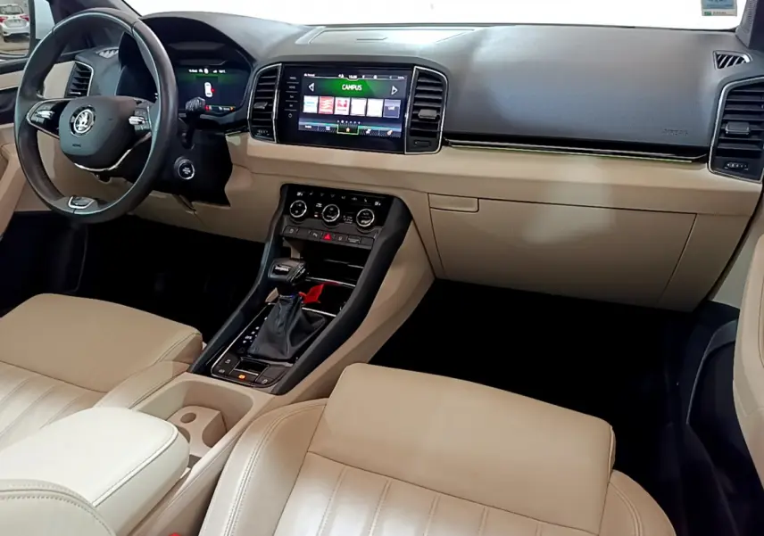 Vue intérieure avant droite du Skoda Karoq 2023 avec sellerie beige, tableau de bord noir et écran tactile central.